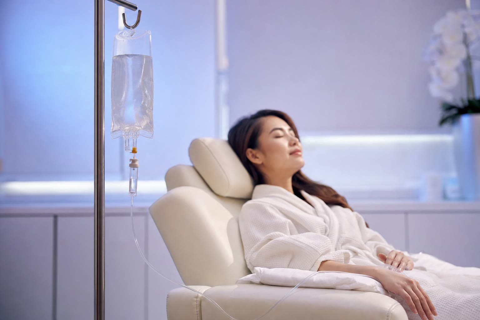 Titisan vitamin IV jernih di sebelah pesakit berehat di kerusi wellness yang tenang